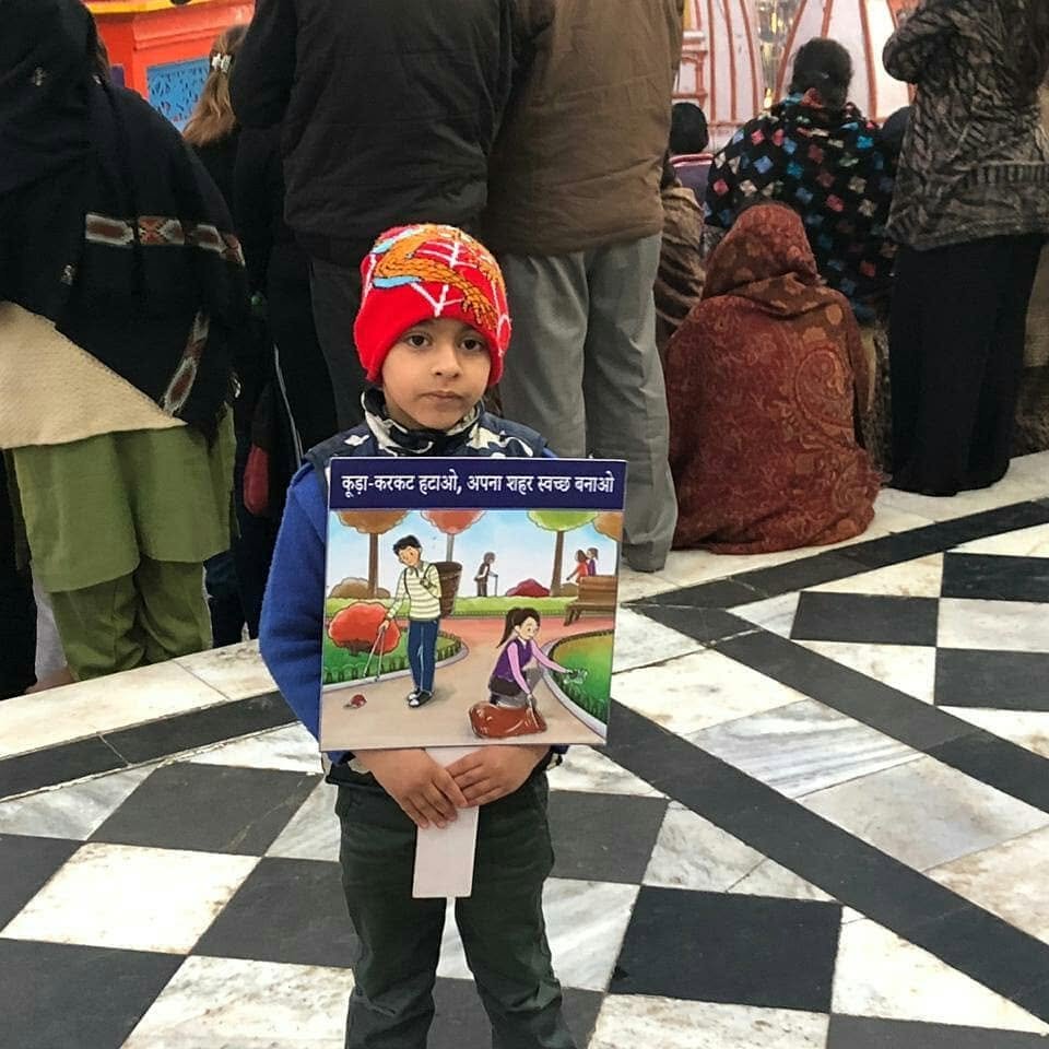 A young Dhananjay holding a cleanliness-awareness poster urging people to clear litter and keep their city clean, at a public gathering
