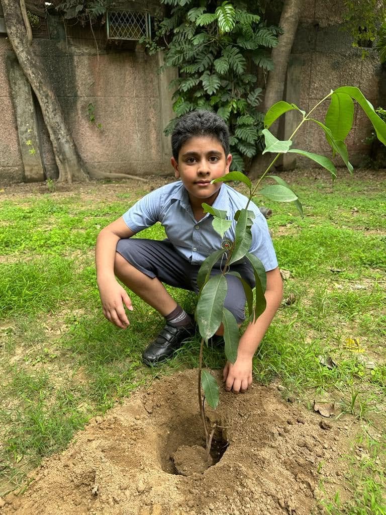 Dhananjay in school uniform planting a tree sapling
